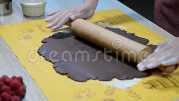 女性手在白色桌子上用擀面杖擀制巧克力面团烹饪课的概念视频的预览图