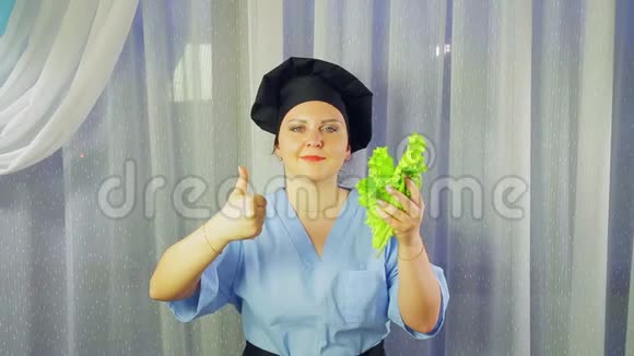 女厨师穿着围裙微笑手里拿着绿色沙拉用手展示课堂视频的预览图