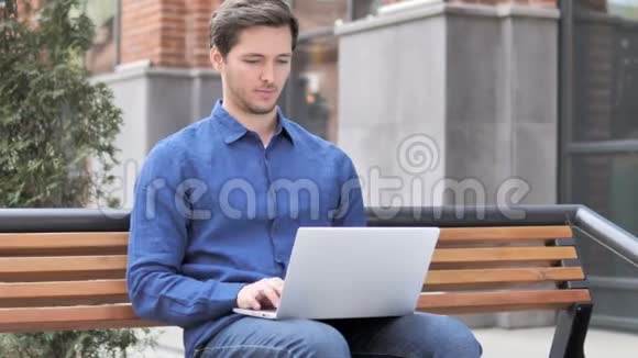 坐在长凳上的年轻人在网上聊天视频的预览图