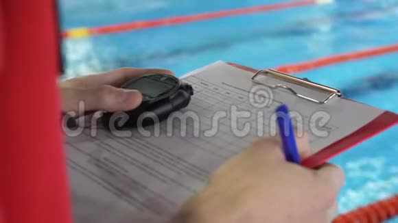 在泳池里竞争的裁判法官的特写把证词记录在案的水池里视频的预览图