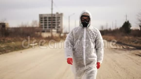 穿着防护服装和防毒面具的病毒学家在工业工厂的一个荒无人烟的城市里散步视频的预览图