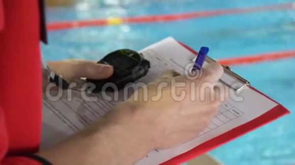 在泳池里竞争的裁判法官的特写把证词记录在案的水池里视频的预览图