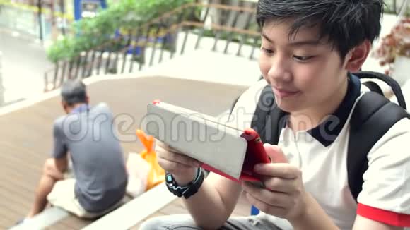 亚洲男孩在平板电脑上玩着笑脸泰国男孩在平板电脑上看着慢动作放松视频的预览图
