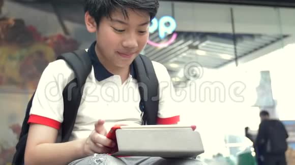 亚洲男孩在平板电脑上玩着笑脸泰国男孩在平板电脑上看着慢动作放松视频的预览图