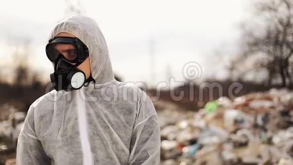 穿戴防护服装和防毒面具的病毒学家在垃圾填埋场附近行走污染生态灾害视频的预览图
