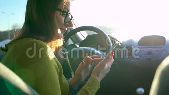 戴眼镜的女人在车里用智能手机系紧安全带驾驶汽车引擎视频的预览图