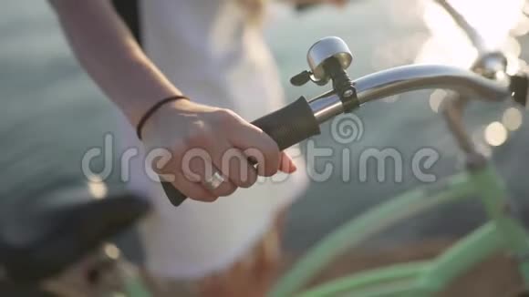 在自行车车把上的女性手特写镜头日落或日出时海上迷人的年轻女子视频的预览图