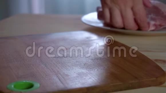 家庭主妇把新鲜的猪肉牛排放在桌子上把盐洒在上面视频的预览图