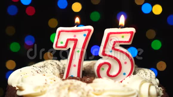 在蛋糕上的75号75岁生日蜡烛燃烧在最后吹灭彩色模糊背景视频的预览图