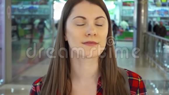 穿着红色衬衫的年轻女子微笑着在购物中心走来走去购物中心走廊的女顾客视频的预览图