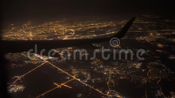从飞机上看到机翼夜晚在城市灯光和街道上飞翔视频的预览图