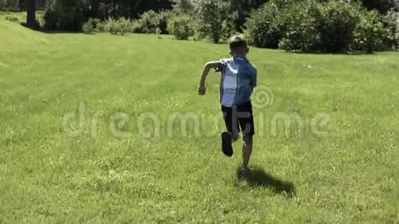 一个有魅力的男孩在公园的草地上跑步夏天心情很好慢动作视频的预览图