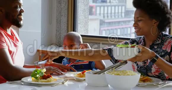 家庭在舒适的家中的餐桌上吃东西视频的预览图