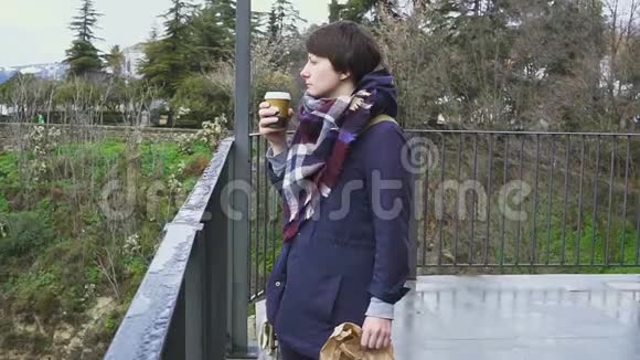 一位年轻女子在山景和古城背景下喝咖啡的肖像视频的预览图