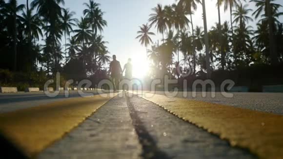 一对夫妇在棕榈树之间的阳光大道上奔跑慢动作1920x1080视频的预览图