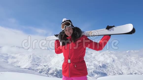 微笑的女子滑雪者站在山顶上肩上拿着滑雪板视频的预览图