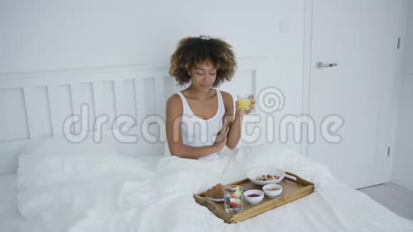 有智能手机的女人在床上吃饭视频的预览图