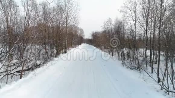 冬天的路在雪地里空中镜头摄像机慢慢向前移动视频的预览图