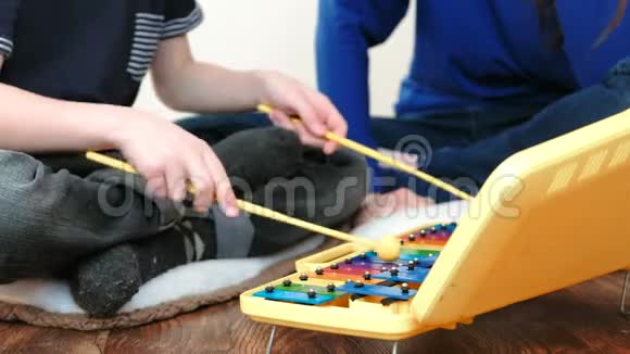 演奏音乐乐器特写男孩他的手拿木棍玩木琴他妈妈坐在他身边视频的预览图