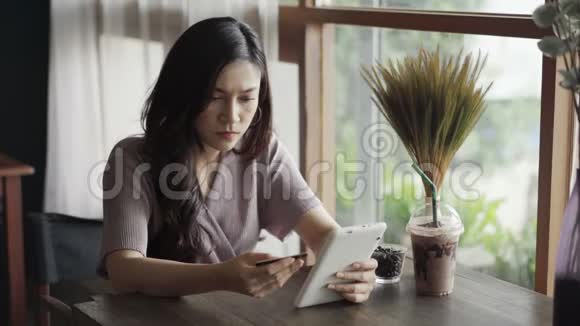 有信用卡问题的女强人在咖啡馆用平板电脑上网购物视频的预览图
