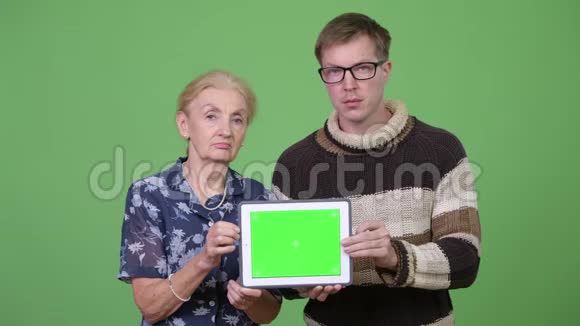 快乐的奶奶和孙子一起展示数码平板电脑视频的预览图