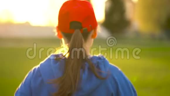 日落时分女人穿过体育场后景慢动作视频的预览图