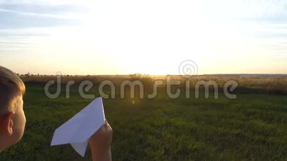 这个男孩带着一架纸飞机沿着绿色的田野向阳光奔跑视频的预览图