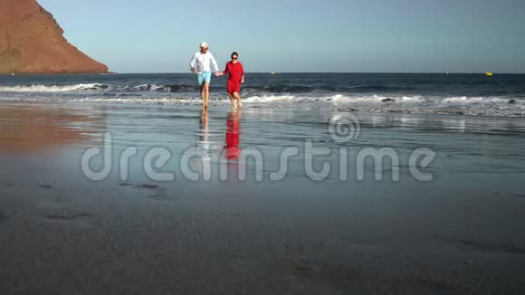 恋爱中的夫妻无忧无虑地从水里跑出来向海滩上的人挥手海洋海岸图片视频的预览图