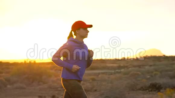 日落时女人沿着荒无人烟的地方奔跑背景上的山脉慢动作视频的预览图
