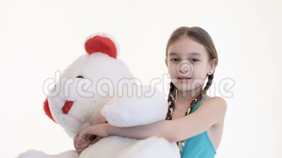 画室的白色背景上一个扎着辫子抱着一只大泰迪熊的可爱白人女孩的肖像视频的预览图