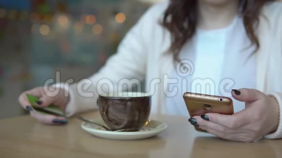 有电话和信用卡的女人在咖啡馆的桌子上视频的预览图
