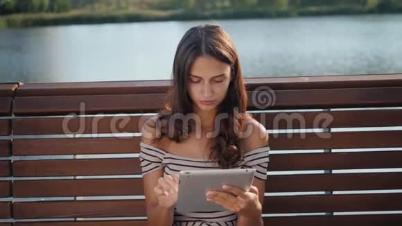 快乐的年轻学生坐在长凳上在一个夏天的公园里看书一位美丽的姑娘视频的预览图