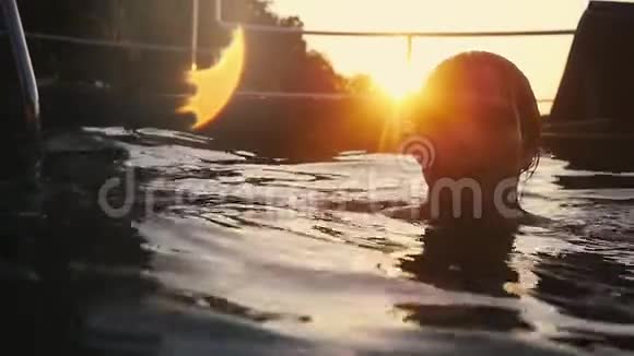 年轻的帅哥在美丽的夕阳下在游泳池里放松慢动作1920x1080视频的预览图