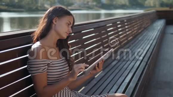 快乐的年轻学生坐在长凳上在一个夏天的公园里看书一位美丽的姑娘视频的预览图