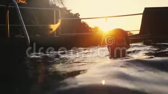 年轻的快乐男子在美丽的日落游泳与镜头耀斑效果慢动作1920x1080视频的预览图