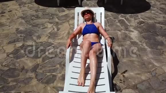 从顶部看一个穿着蓝色泳衣的女人在休息室里打日光浴起床去游泳池在游泳池里游泳视频的预览图