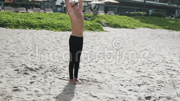 运动赤膊男子在沙滩上做伸展瑜伽练习慢动作稳定射击视频的预览图