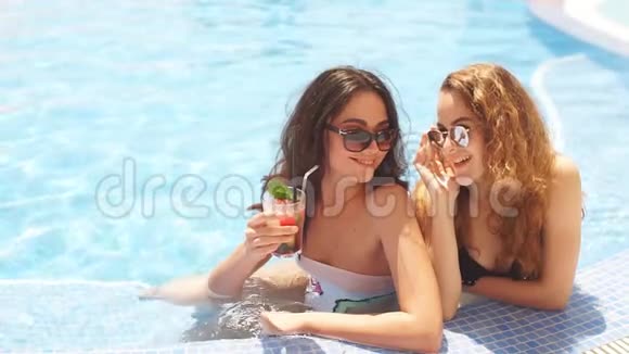 两个漂亮的黑发和金发女孩长发在游泳池附近的太阳视频的预览图