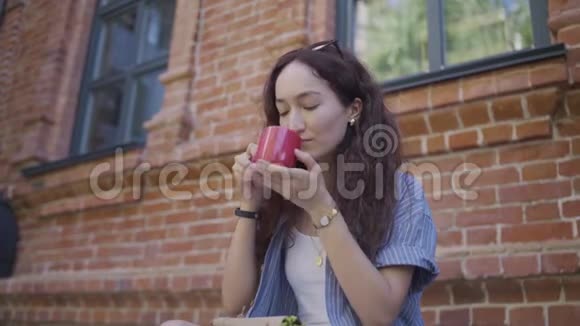 漂亮的女人正在外面喝咖啡一个女孩正在外面喝茶视频的预览图
