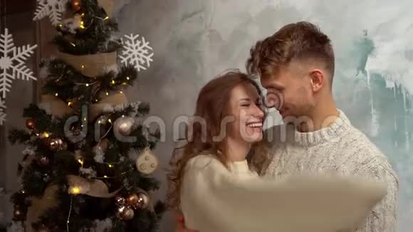 年轻夫妇一起在家过圣诞节在家过拥抱的概念视频的预览图
