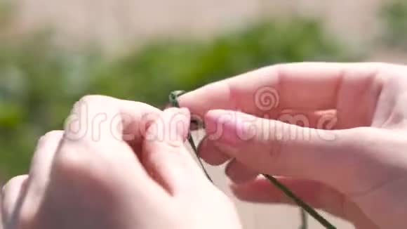 女人从树叶上编织辫子特写视频的预览图
