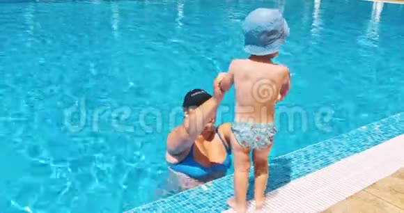 母亲和儿子在度假村游泳池附近的日光浴中放松视频的预览图