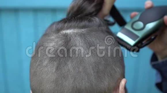 在露天美发沙龙中女性理发师用剪发器给男性理发后景关闭视频的预览图