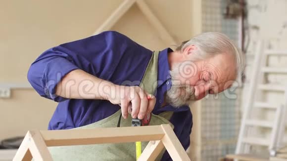 老灰头发的木匠胡子和胡须测量木制娃娃屋视频的预览图