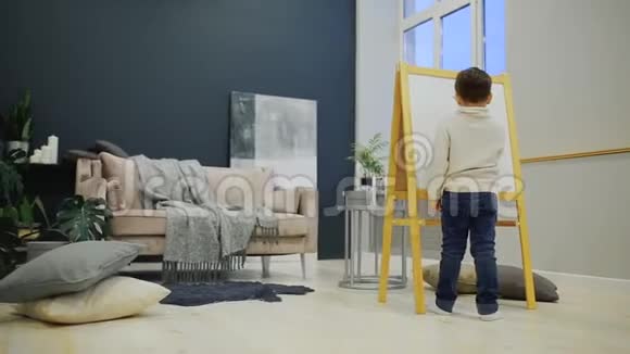 房子客厅里的小男孩在黑板上画着一个孩子画记号学前教育视频的预览图