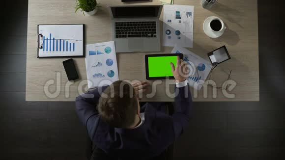 悲伤的商人在绿色屏幕平板电脑上滚动页面抑郁俯视视频的预览图
