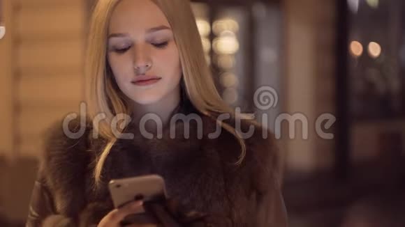 漂亮的年轻女人用智能手机微笑打字留言看着手机微笑使用手机视频的预览图