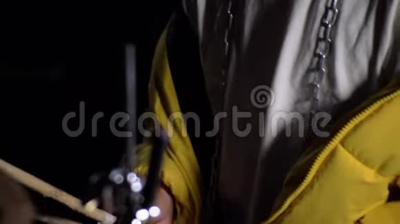 穿着黄色夹克的年轻人在黑暗中打鼓4K视频的预览图