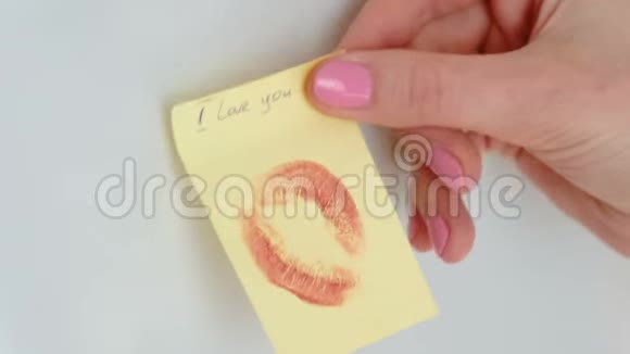 特写女人她的手用吻把纸条粘起来写我爱你在白色的墙上视频的预览图