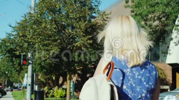 一个带背包的金发女人穿过马路在红绿灯前倒计时生活节奏快视频的预览图